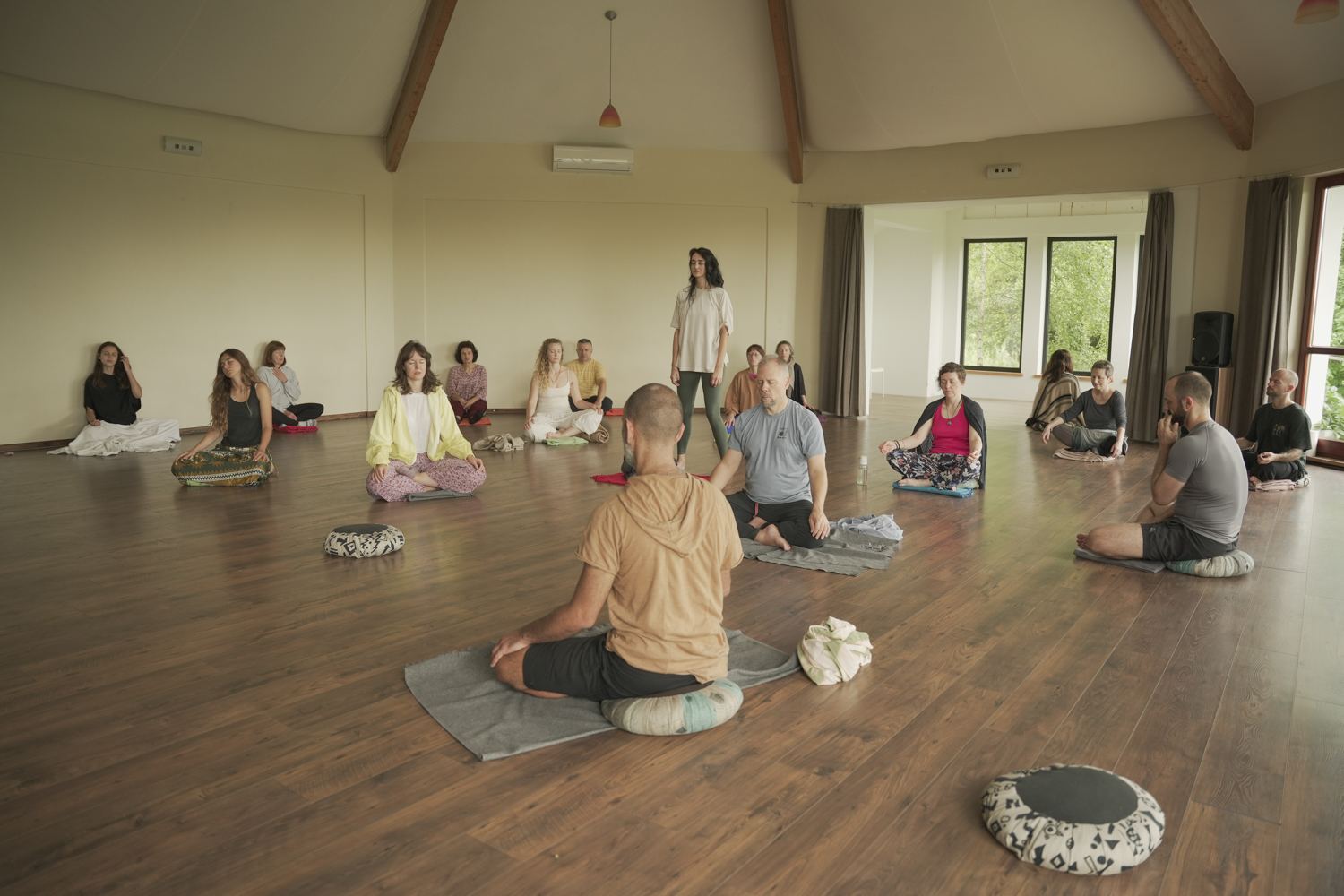 Grupp istub vaikses meditatsioonis patjadel valgusküllases saalis